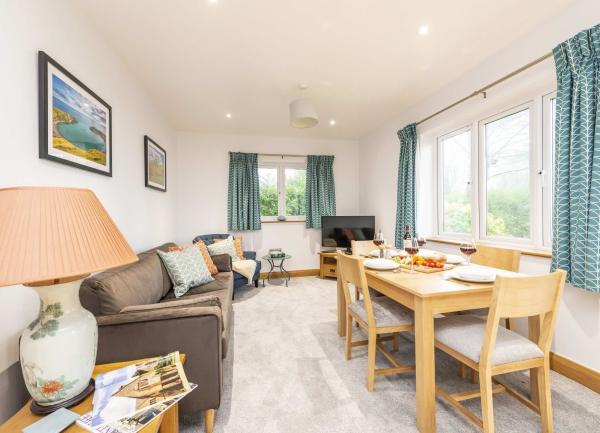 Dual aspect lounge with sofas and a TV with a dining table at one end.