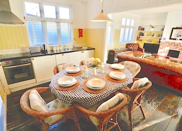 Kitchen-dining area with fitted units, an electric cooker and diing table with 6 wicker chairs.
