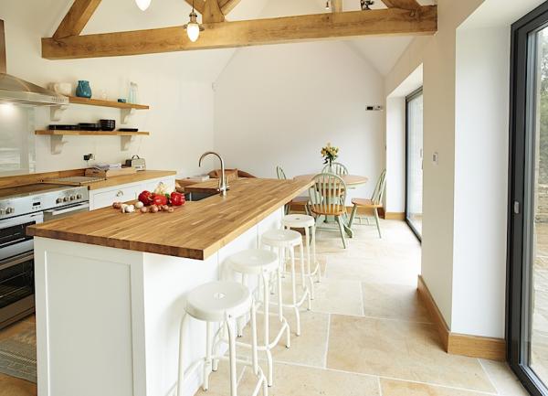 A kitchen breakfast bar with high stools, lies a dining tale with 4 chairs.