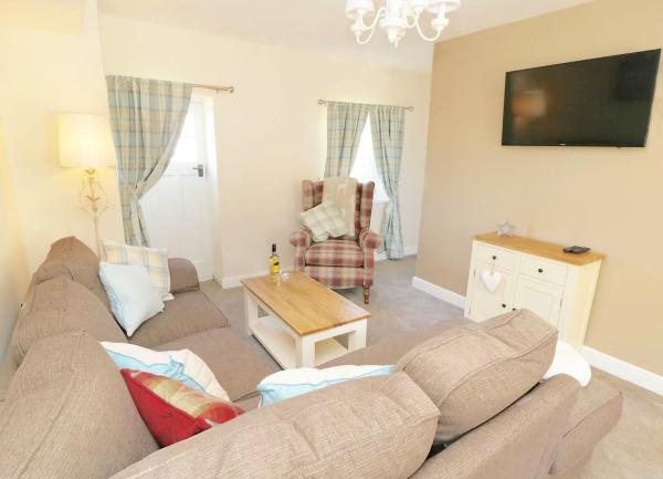 Lounge with wrap-around sofa, armchair and wall-mounted widescreen TV.