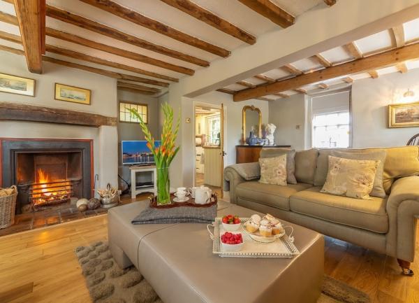 A large, luxurious lounge with oak beam and floors, a sofa and a wood burner.