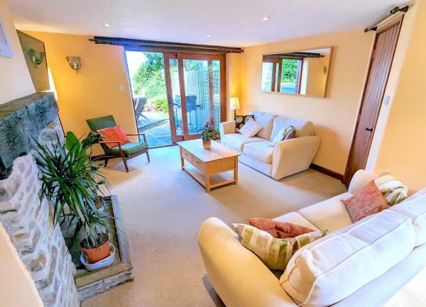 Cottage living room with sofas, coffee table and French windows to garden.