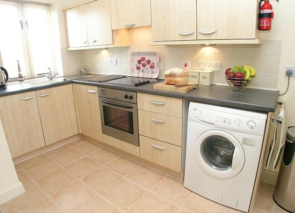 A fitted kitchen with floor and wall-mounted cupboards, dishwasher and cooker. 