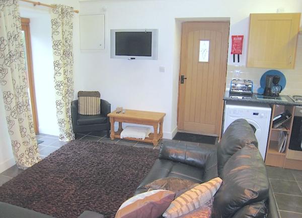 Romeo cottage lounge with soft leather sofa, armchair and TV.