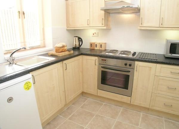 Kitchen corner with fitted units, oven, microwave and fringe.