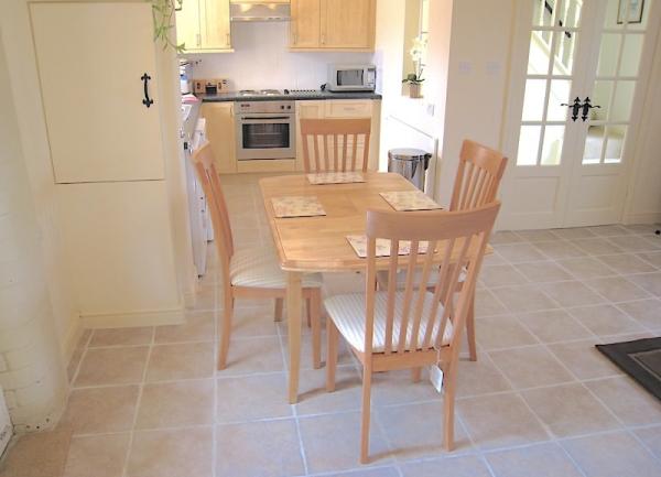 A dining table and chairs for 4 guest with a kitchen in the background.s