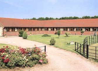 A large L-shaped single-storey holiday lodge surrounded by lawns.