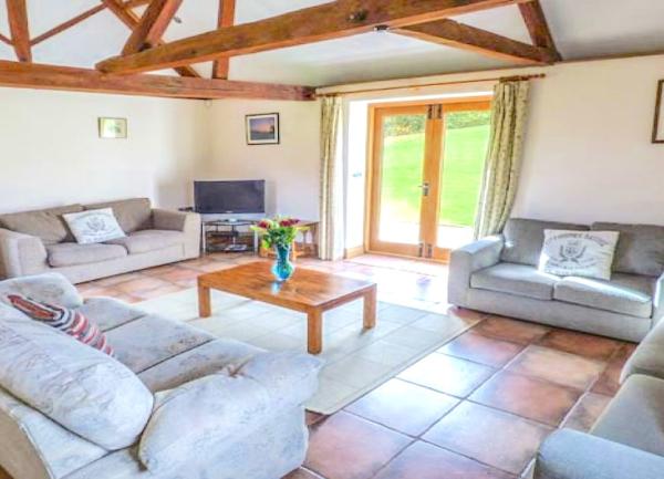 A spacious pine-beamed lounge with 4 sofas, TV and coffee table.
