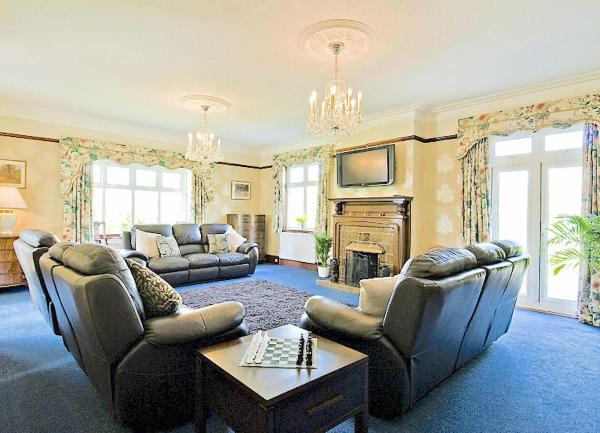 Spacious lounge with three sofas around a fireplace.