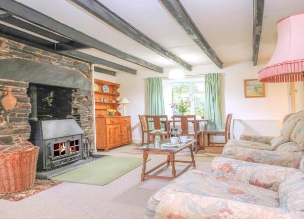 An oak-beamed lounge with an inglenook fireplace contains a sofa, TV, dining and coffee tables.