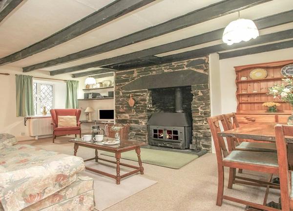 Lounge corner with a wing-back armchair, TV and inglenook fireplace with a wood burner and log basket.