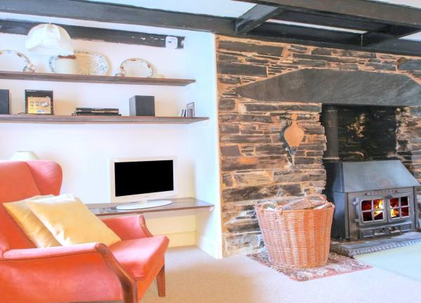 A carpeted lounge with matching sofas and armchairs on one side and an inglenook fireplace with a wood burner on the other.