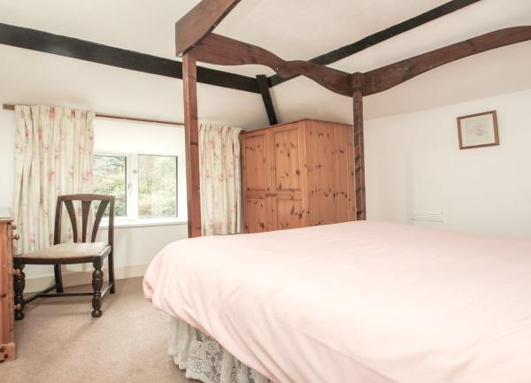 An oak-beamed double bedroom with a large bed and wardrobe.