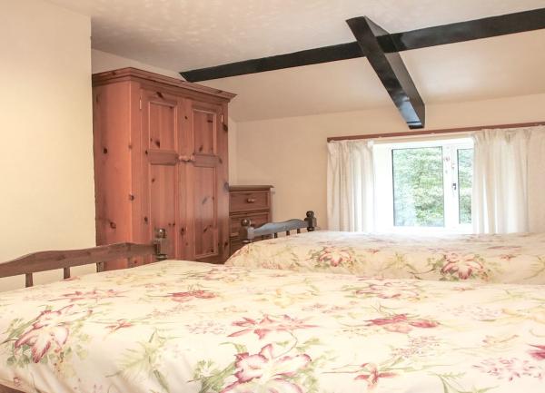 A twin bedroom with beds, wardrobe, chest-of-drawers and a double window.