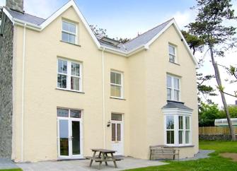 Exterior of a rural, 3-storey coastal holiday home and garden.