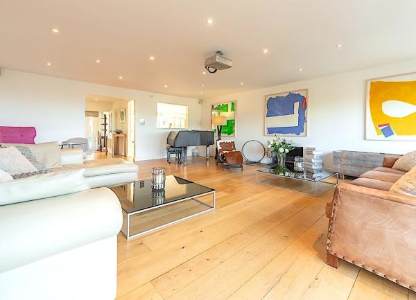 A spacious lounge with 3 sofas, a widescreen TV and a coffee table.