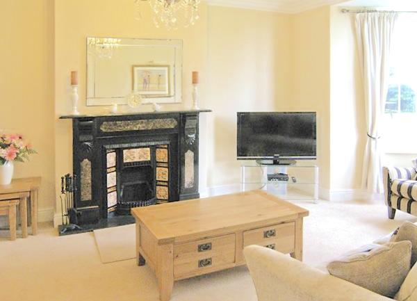 Spacious lounge with a bay windoow and Victorian fire place with tiles, TV coffee table and  armchairs.