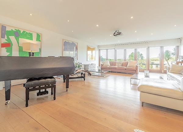 A lounge with sofas, piano and bi-fold French doors to a garden.