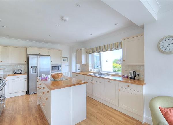 A smart-looking fitted kitchen with an island block and American-style fridge-freezer.