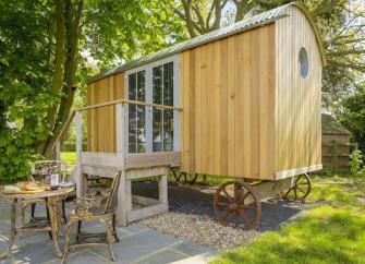 Herefordshire Shepherds Hut is shaded by trees in a garden.