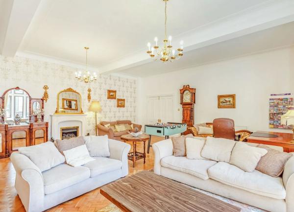 A luxurious and spacious lounge with sofas, side tables and a grandfather clock.