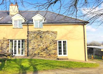 Exterior of a stout North Devon farm cottage overlooking a garden.