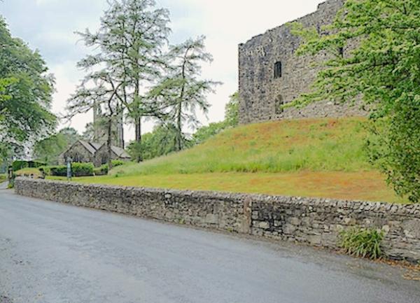 The exterior of Lydford Castle ruins on a raised bank.