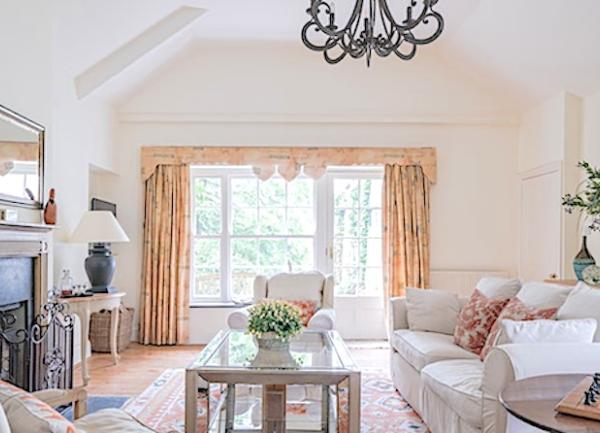 A stylish, spacious lounge with comfortable sofas and armchairs facing a fireplace with a csast-iron fireguard. At one end  is a tall sash window with a coffee table in the room's centre.