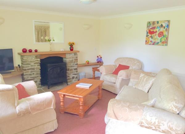 A cosy country cottage lounge with a 3-piece suite, wood burner and TV.