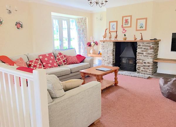 A lounge with a sofa, armchair, TV and a wood-burner.