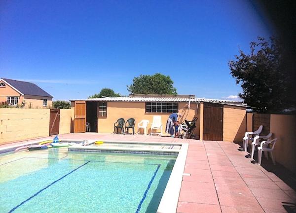 An outdoor swimming pool with chairs and sun-loungers on the poolside terrace.