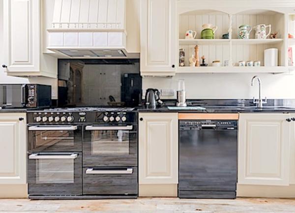 A bespoke fitted kitchen with floor and wall-mounted cupboards incorporating two cookers and a dishwasher.