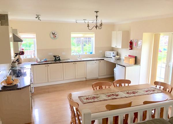 A farmhouse kitchen-diner with fitted units, ceramic hob, oven, fridge, dishwasher and French windows to a garden.