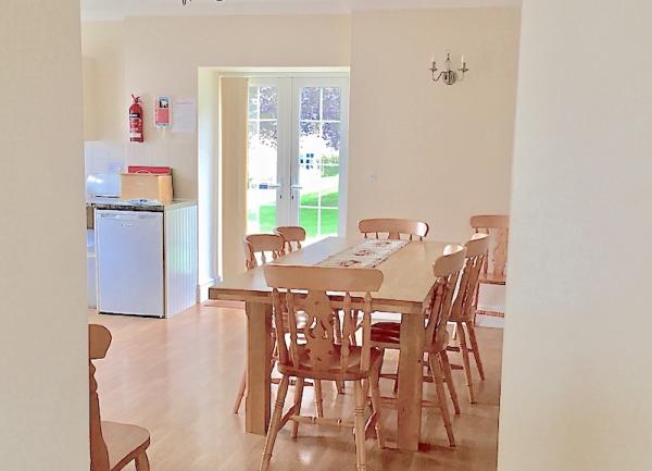 A dining table and 6 chairs with a French Window to a garden at the end of the room.