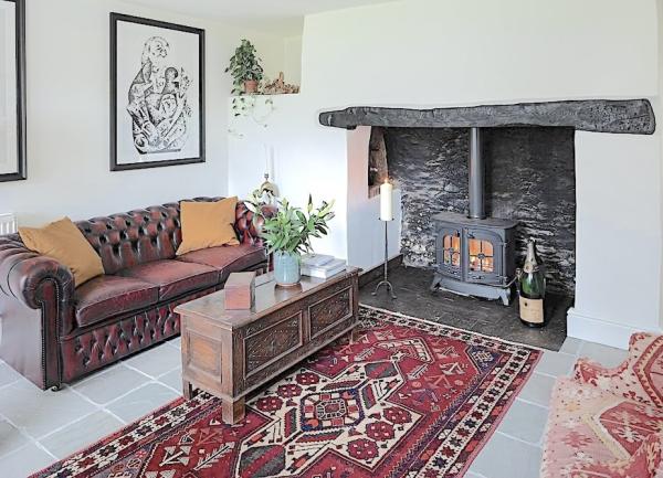 Exmoor cottage lounge with a wood-burner in an inglenook fireplace, a sofa, armchair and coffee table.