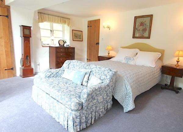 A double  bed with twin bedside table and lamps and a chintz sofa in a North Devon cottage studio for two.