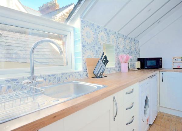 A fitted kitchen with washing machine, microwave, toaster and knife block.