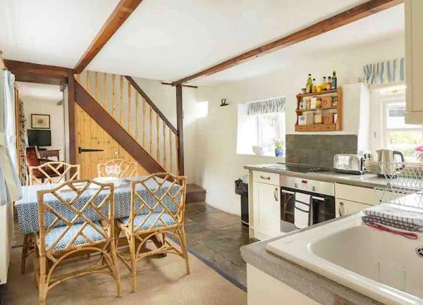 A kitchen diner with a oven, fridge, a dining table seating four and stairs to 1st floor.