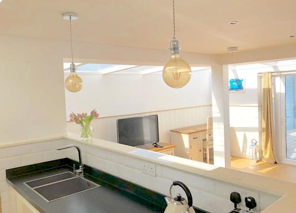 Fitchen worktops and a sink with a mixer tap face the dining area in a seaside holiday cottage