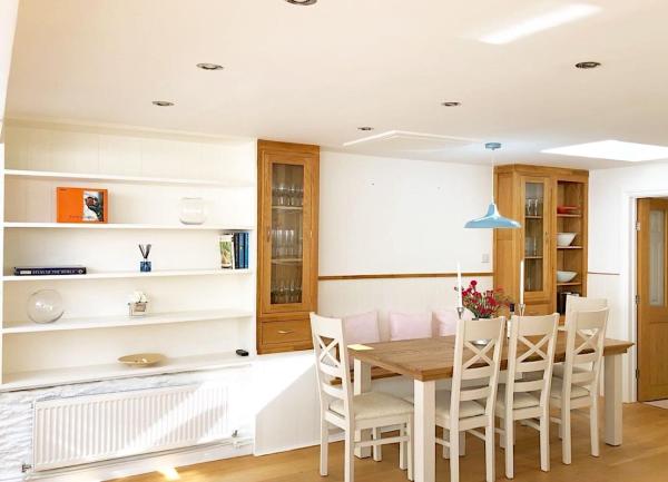 A dining table and seven chairs adjacent to a kitchen area.
