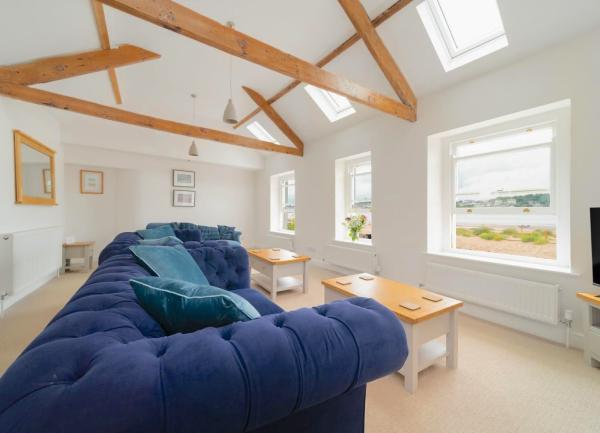 Lounge with big comfortable sofas, coffee tables, TV and sea views through three windows.
