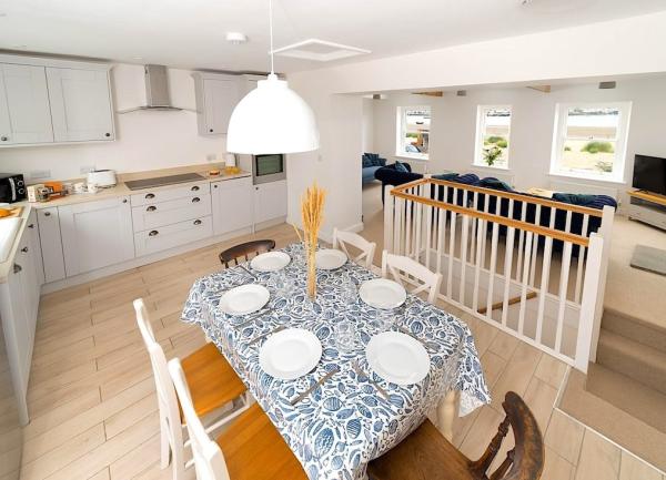 Open-plan living with a fitted, well-equipped kitchen, dining table and a lounge with sofa and wide-screen TV.