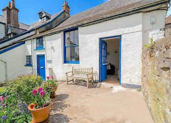 Exterior of a single-storey holiday cottage overlooking a courtyard.