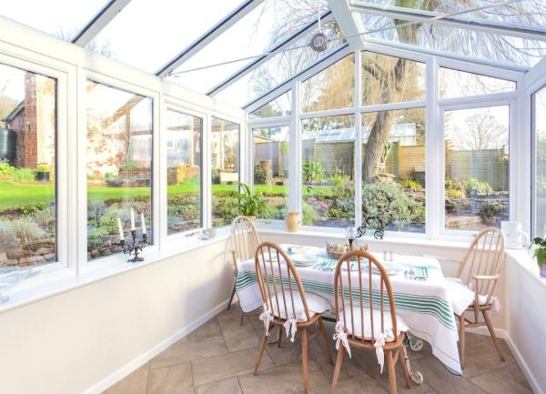 A glass-roofed conservatory in use as a dining room with a table for four.