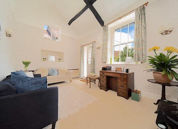 A spacious Devon lounge with furniture including a sofa, armchairs and an antique writing desk.