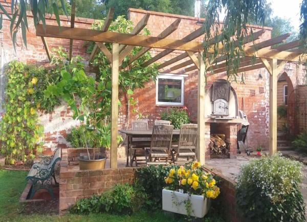 Cottage exterior with a large arbour over a BBQ terrace.