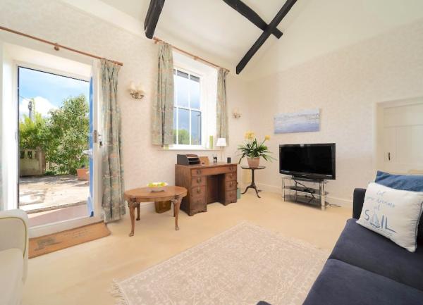 A lounge with French windows to a garden, desk, sofa and a TV.
