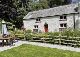 The exterior of a stone-built country cottage overlooks a pretty garden.