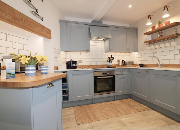 Kitchen with tiled walls and fitted cupboards on three sides incorporating appliances including an oven.