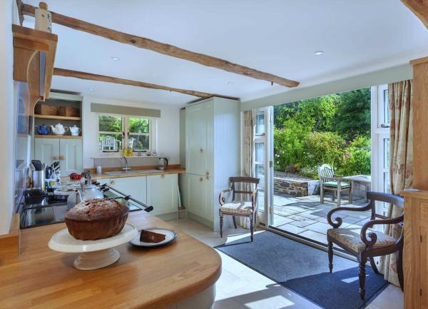A kitchen with fitted units and appliances opposite a row of bi-fold glass door that open onto a garden.